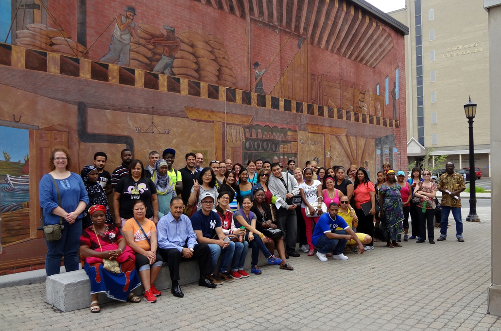 Visitors’ group photo in front of the mural outside the Erie Canal Museum’s entrance. 